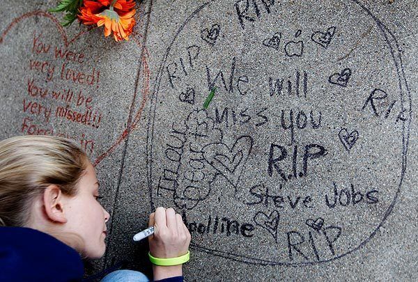 Apolline Arnaud, 12, a neighbor of Apple co-founder Steve Jobs, writes a message in front of Jobs' home in Palo Alto, Calif. Jobs died Wednesday. He was 56.