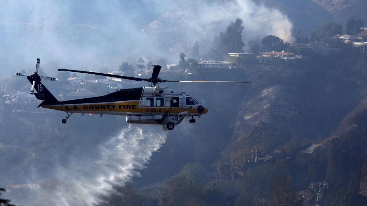 An L.A. County firefighting helicopter drops water along a row of homes threatened by the Skirball fire in Bel-Air.