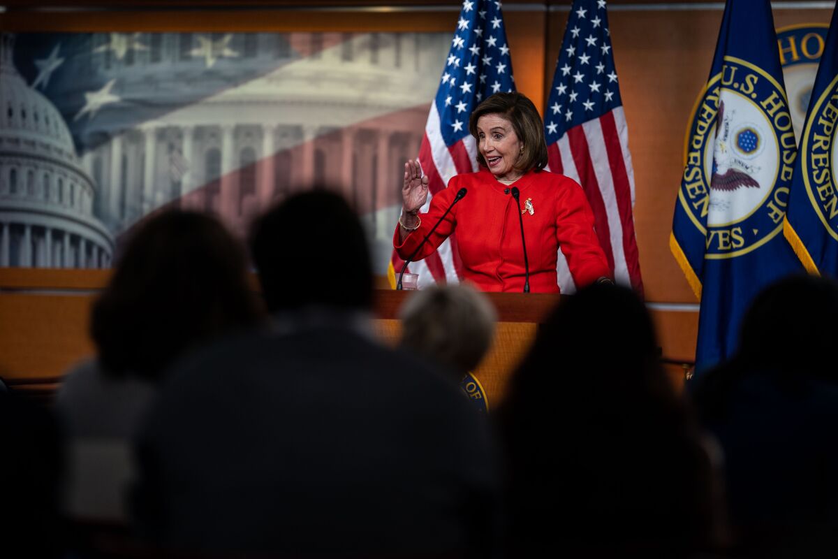 House Speaker Nancy Pelosi speaks at a lectern with American flags behind her