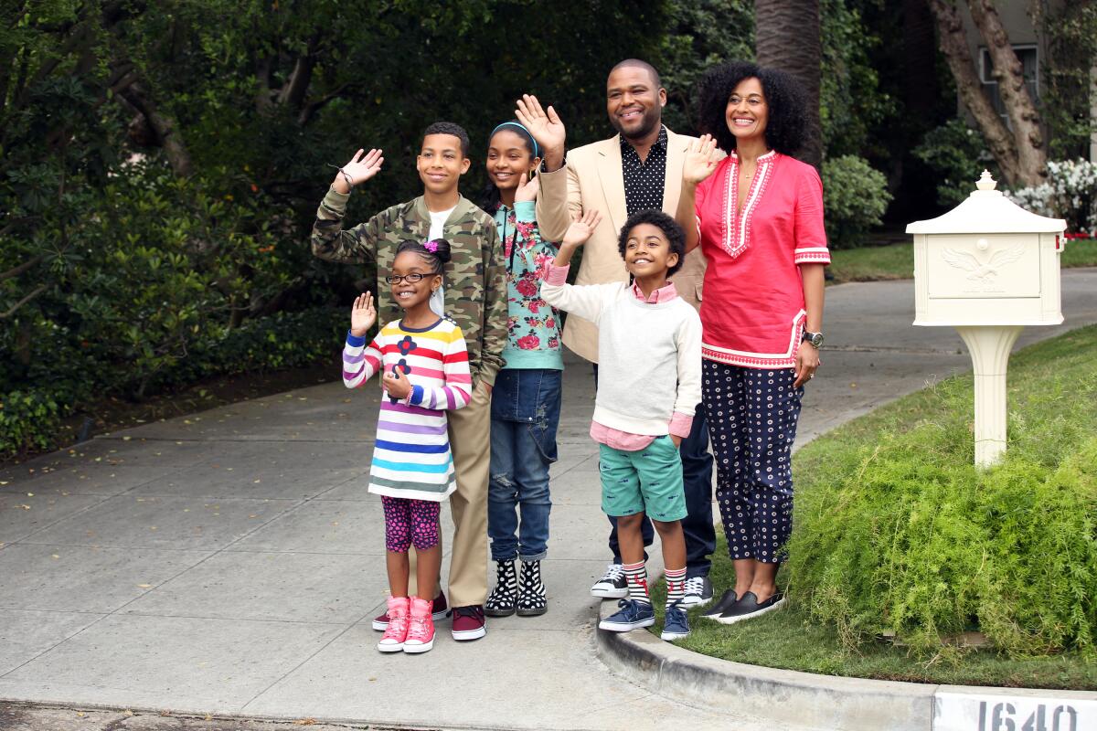 A family stands next to a mailbox waving.