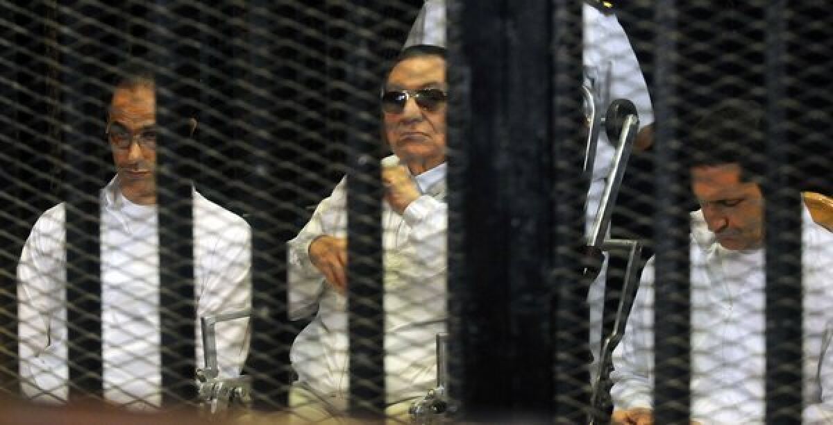 Former Egyptian President Hosni Mubarak, center, and his sons Gamal, left, and Alaa are seen behind bars during a court appearance Sunday in Cairo.