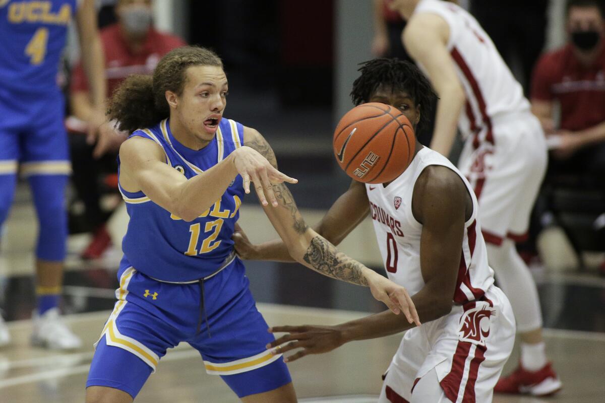UCLA forward Mac Etienne passes the ball in front of Washington State center Efe Abogidi.