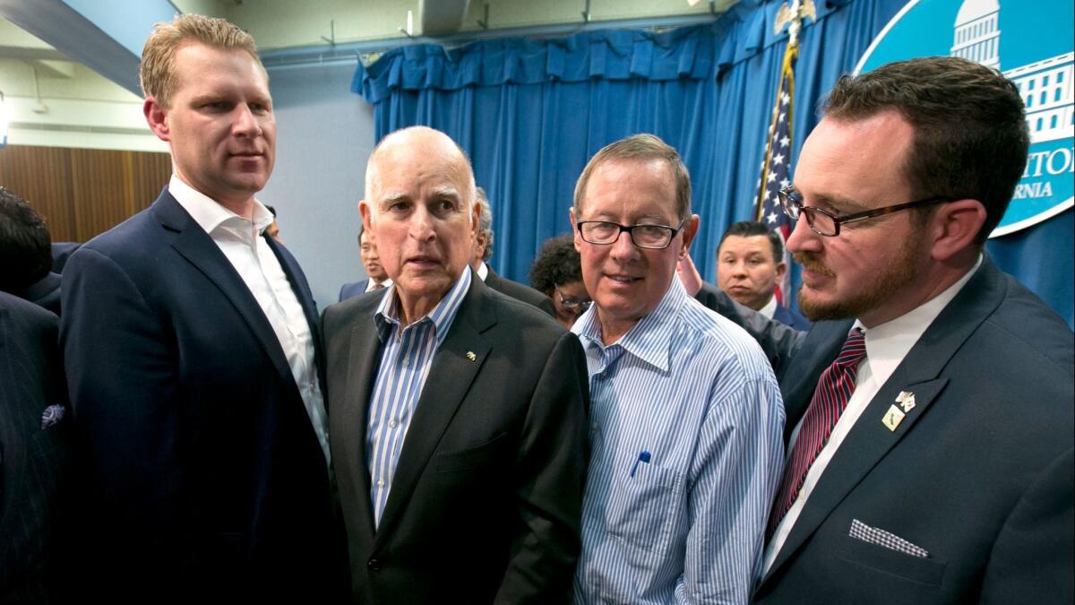 Gov. Jerry Brown, flanked by Republican legislators Chad Mayes, left, Tom Berryhill, second from right, and Devon Mathis, right, on July 17, after the Legislature approved an extension of cap and trade.