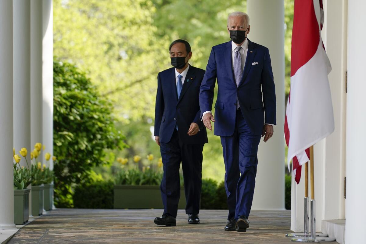President Biden and Japanese Prime Minister Yoshihide Suga walk to a Rose Garden news conference after their meeting Friday.