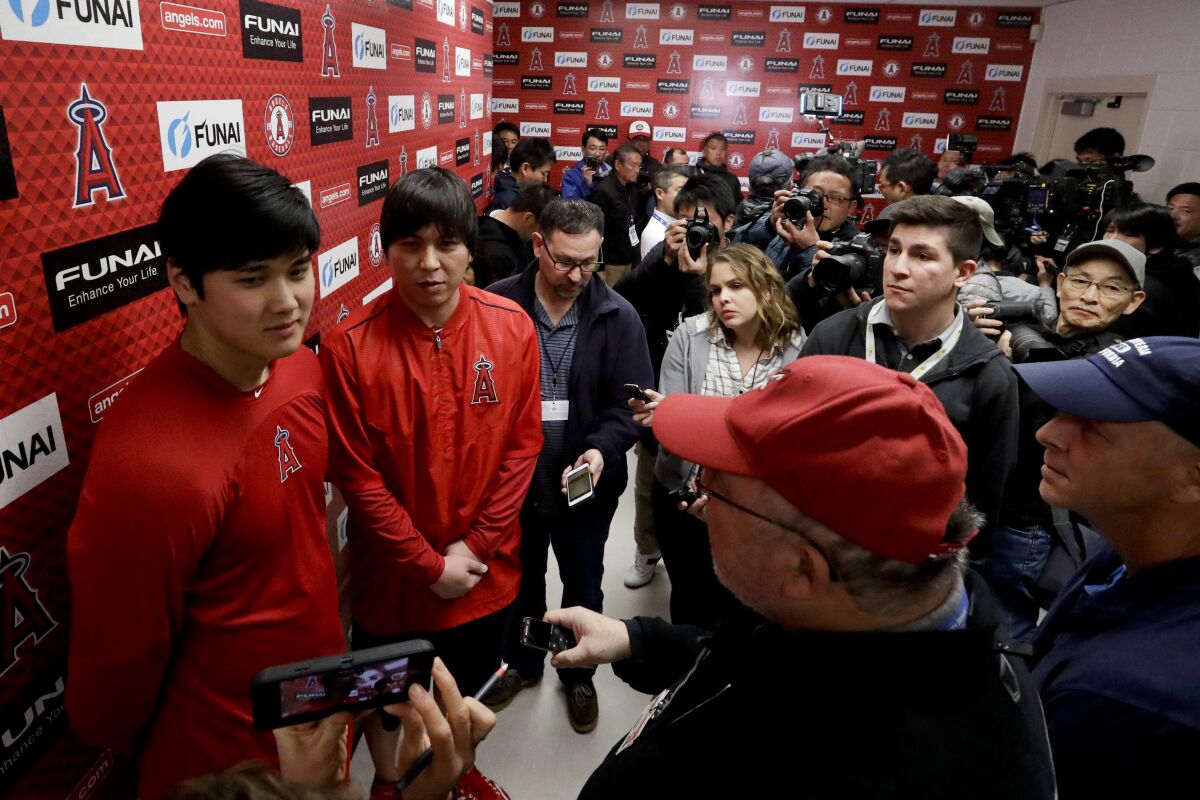 The Angels' Shohei Ohtani, left, speaks to the media at the baseball spring training facility