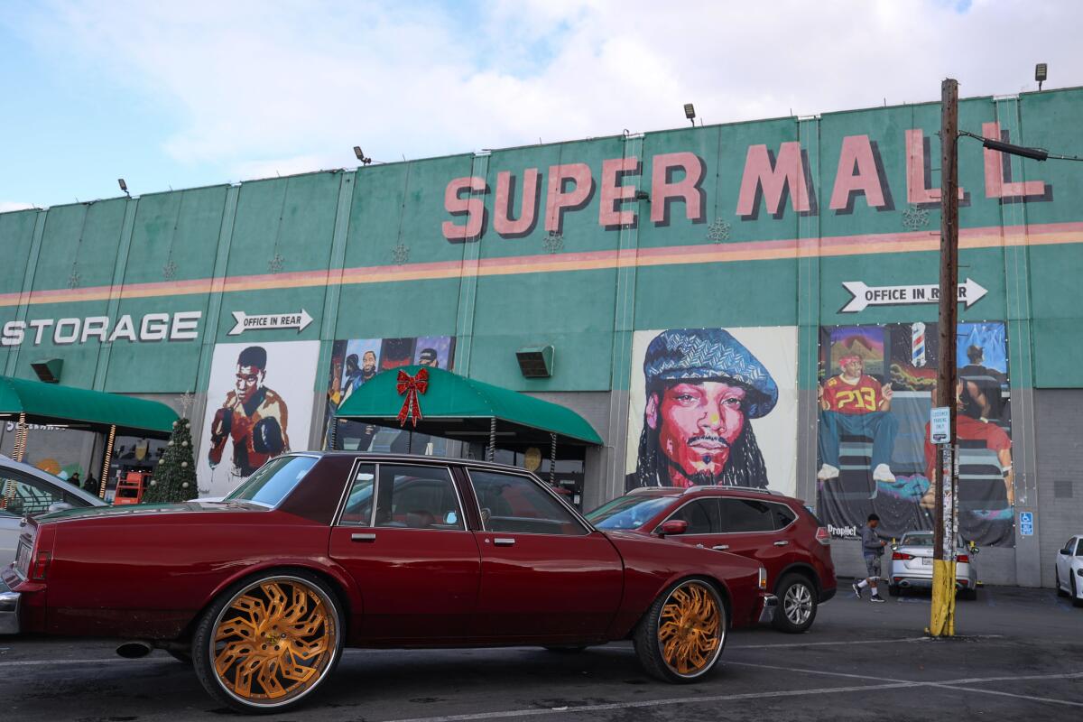 A few cars are parked in front of a building with the words "Super Mall" on it.