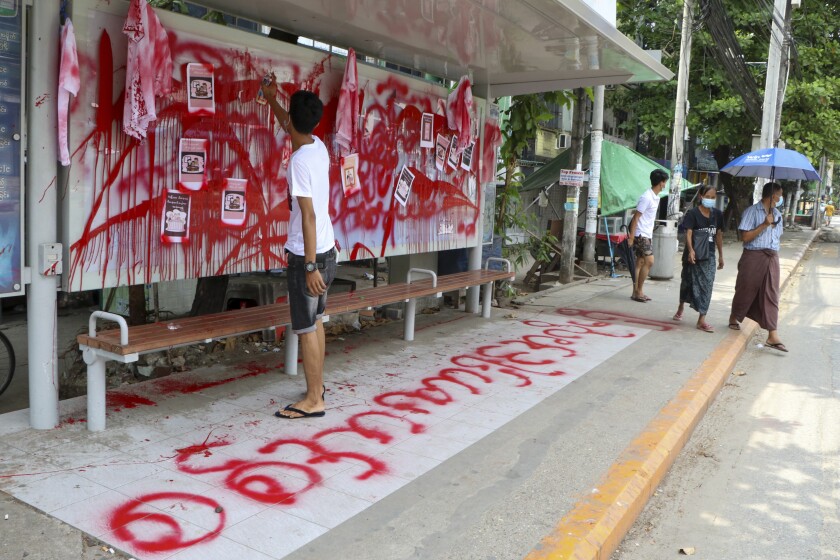 An anti-coup protester uses red paint as he writes slogans at a bus stop on Wednesday April 14, 2021 in Yangon, Myanmar. Anti-coup protesters kept public demonstrations going despite the threat of lethal violence from security forces. The words reads "We do not accept military coup". (AP Photo)
