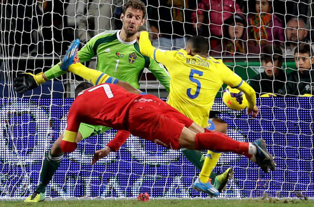 Portugal forward Cristiano Ronaldo (7) scores on a diving header past Sweden defender Martin Olsson (5) and goalkeeper Andreas Isaksson on Friday in a World Cup qualifying playoff in Lisbon.