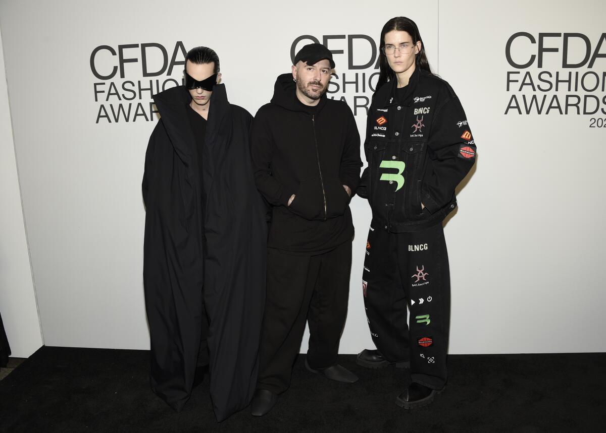 Three men in black outfits posing for photos