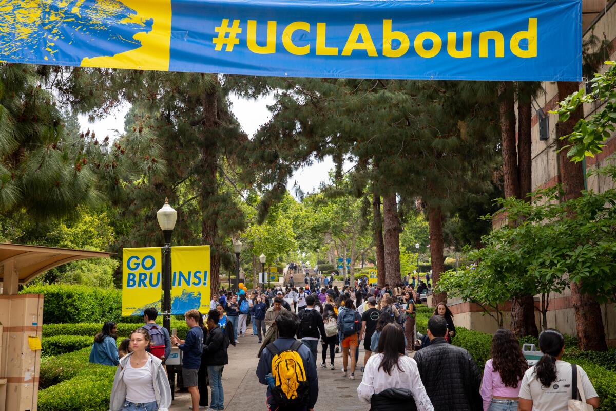 People walk under a banner with the word "#UCLAbound."