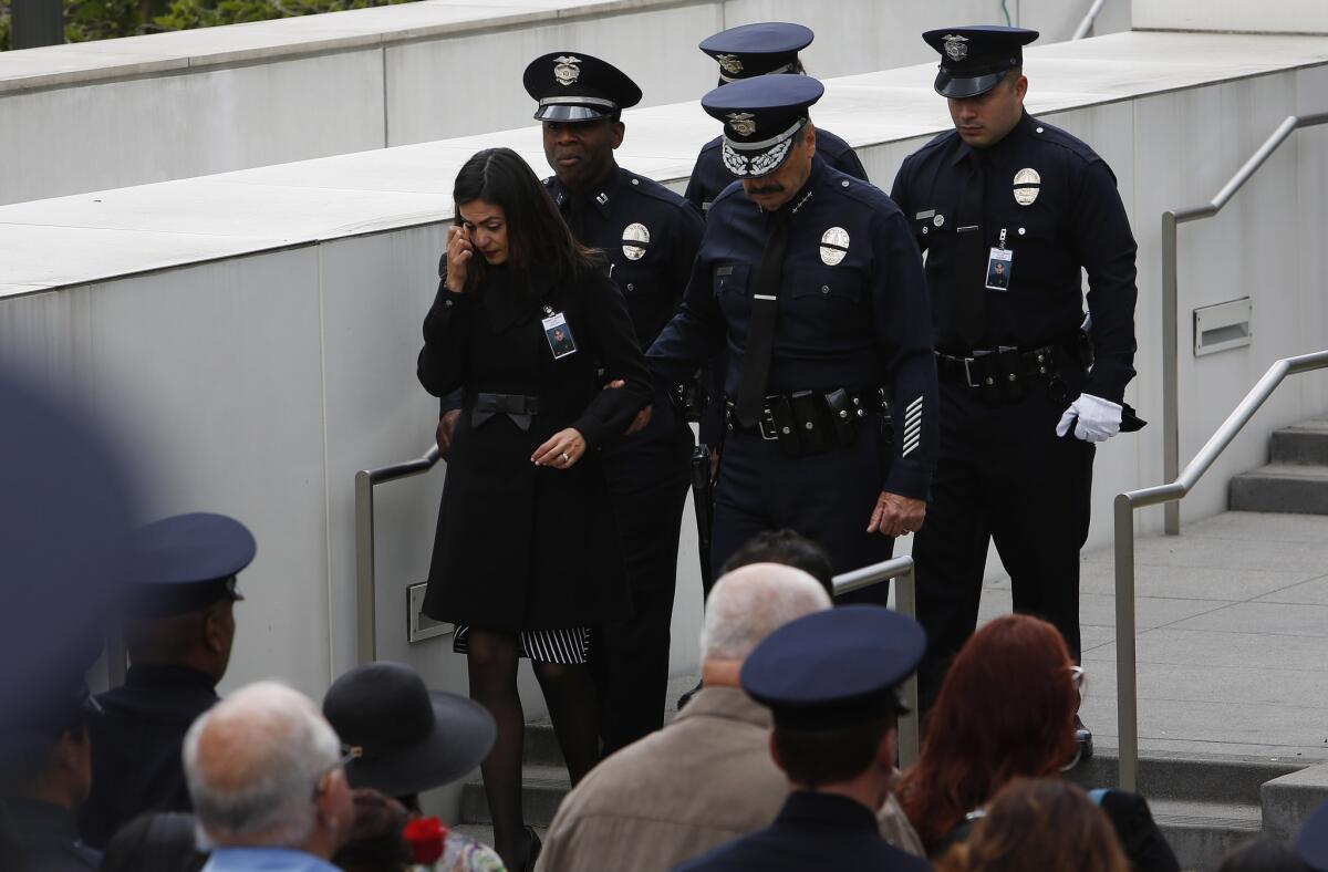 Sonia Sanchez -- the widow of LAPD officer Roberto Sanchez, who was killed May 3, 2014, when an SUV struck his patrol car -- is escorted by Police Chief Charlie Beck during the annual memorial service at downtown headquarters for LAPD officers killed in the line of duty.