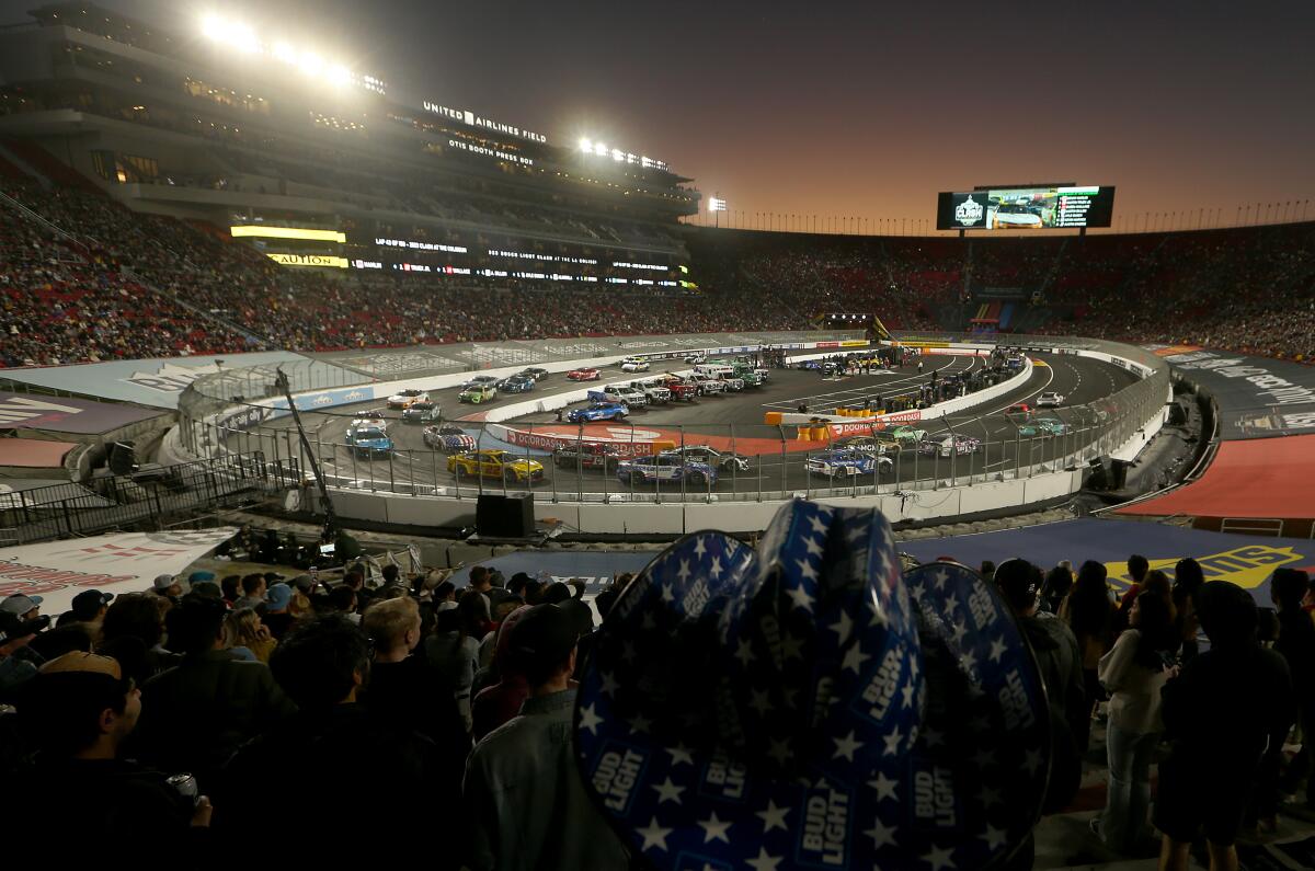 Cars race around a quarter-mile oval at sunset at the Coliseum 