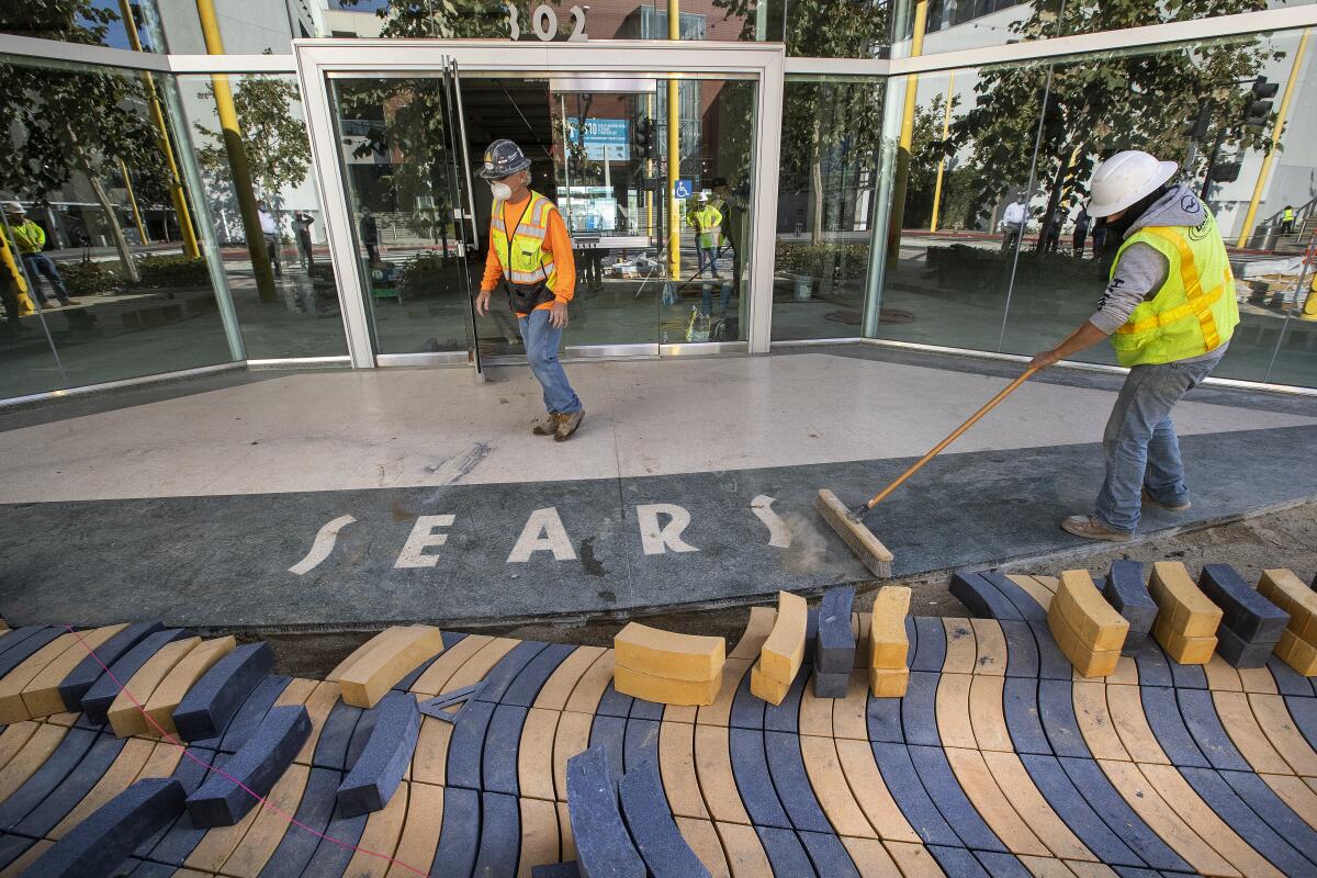 Workers sweep away dirt from the vacant Sears store in Santa Monica on Nov. 18, 2020. 