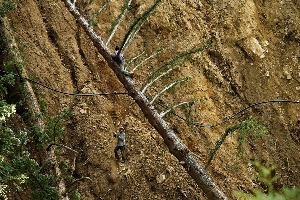 Workers climb a massive slide area above Post Creek near the Ventana Inn in order to replace a water line that had been severed by debris.