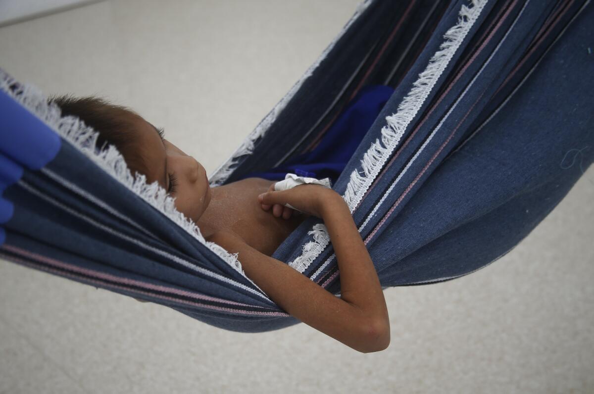 A Yanomami toddler lies on a hammock after receiving medical treatment.