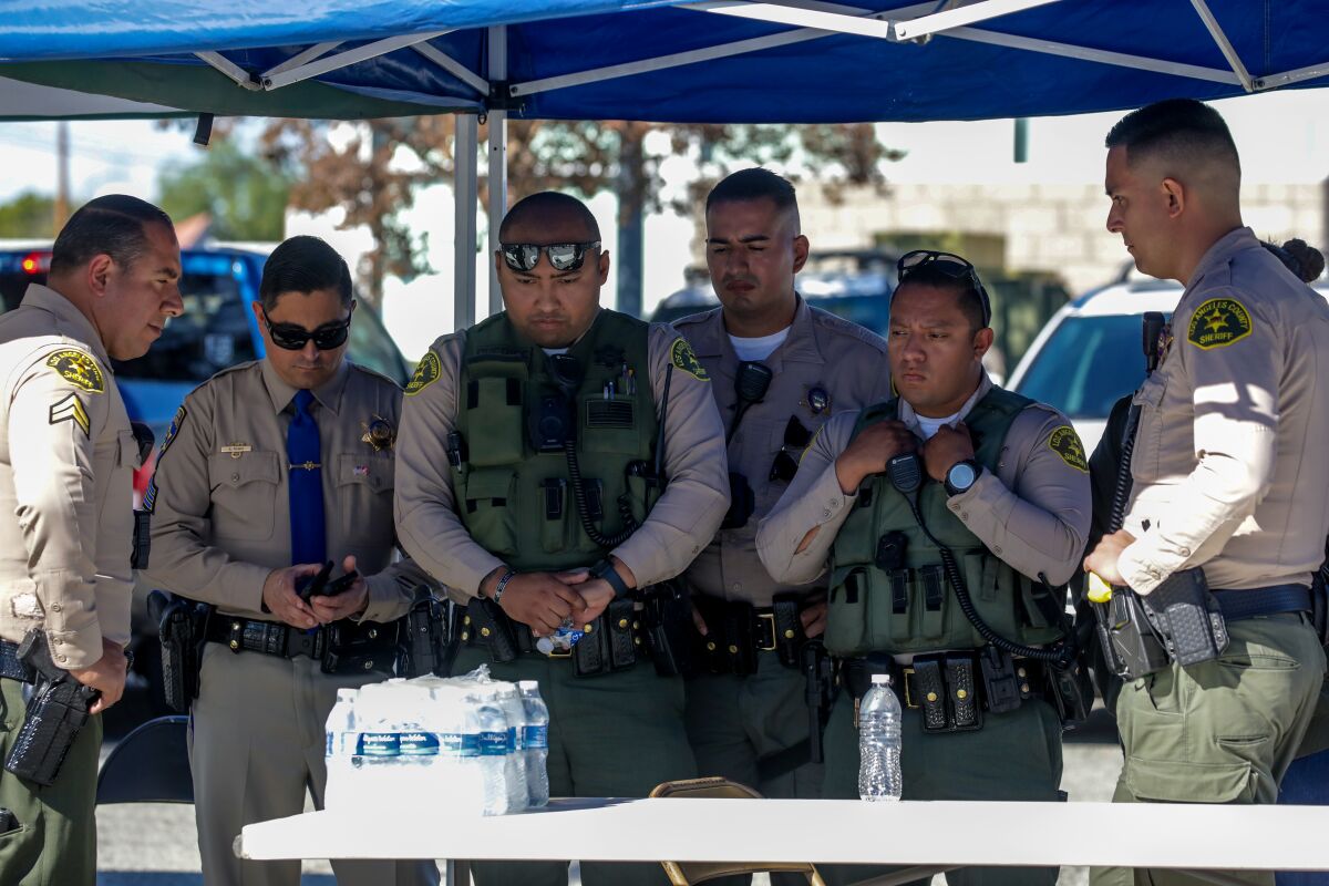 L.A. County sheriff's deputies huddle around a mobile phone 