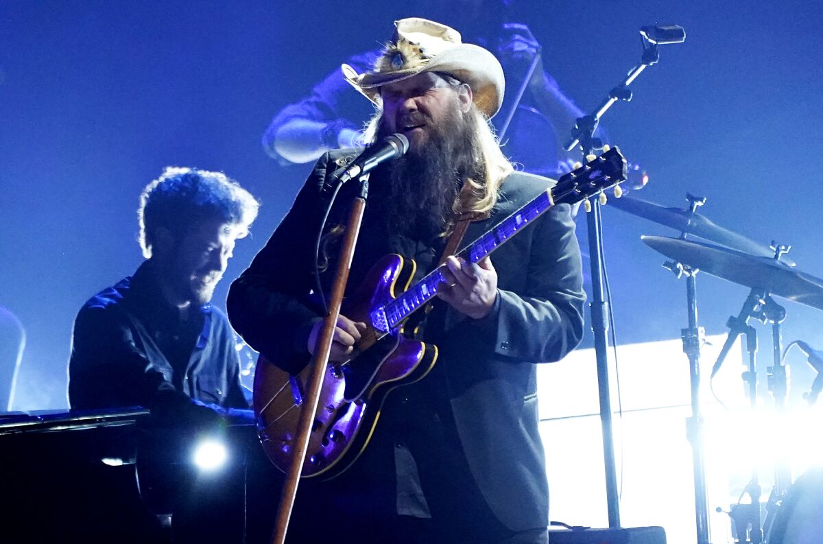 A man in a cowboy hat plays electric guitar and sings onstage.