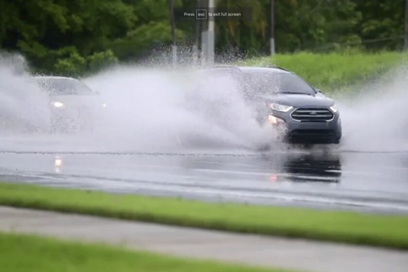 En esta imagen, tomada de un video, autos conducen por una carretera inundada en Canovanas, Puerto Rico, el 30 de julio de 2020. (AP Foto)