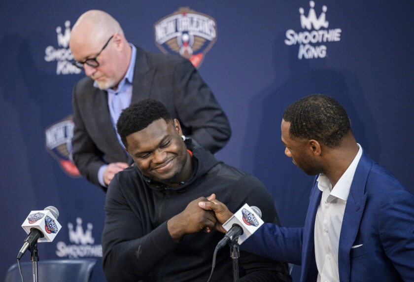 New Orleans Pelicans forward Zion Williamson shakes hands with New Orleans Pelicans head coach Willie Green with New Orleans Pelicans vice president of basketball operations David Griffin standing in the background after talking to the media about signing his contract extension at the Dryades YMCA in New Orleans, Wednesday, July 6, 2022. (Max Becherer/The Times-Picayune/The New Orleans Advocate via AP)