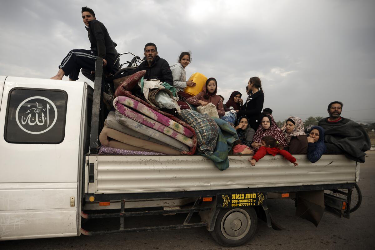 Fleeing Palestinians with children sit on a flatbed truck.