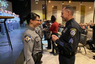 Natalie Young, 22, gets her new deputy badge pinned on by Escondido Police Sgt. Jeff Valdivia, who saved her life as a 6-week-old baby and met her again for the very first time at her graduation ceremony in Colorado Springs on Sept. 23, 2022.