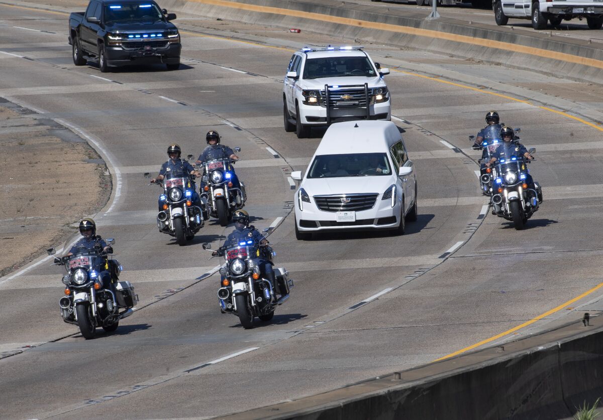 A hearse accompanied by Louisiana State Police motorcycle units carries the body of LSP Master Trooper Adam Gaubert down Interstate 110 from the East Baton Rouge Parish Coroner's Office to Resthaven Gardens of Memory & Funeral Home, Monday, Oct. 11, 2021, in Baton Rouge, La. Gaubert was shot to death early Saturday inside his patrol car during a massive multi-parish manhunt for Matthew Mire, the suspect in that shooting and several others. (Travis Spradling/The Advocate via AP)