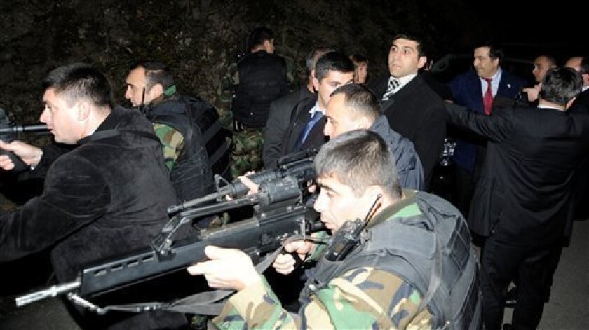 Bodyguards cover Georgia's President Mikhail Saakashvili, second from right in the background, and his Polish counterpart Lech Kaczyinski, not seen, shortly after shots were fired at their motorcade, near the breakaway province of South Ossetia, close to Akhalgori, Georgia, Sunday, Nov. 23, 2008. Saakashvili has blamed Russian troops for the gunfire. Russian Foreign Minister Sergey Lavrov said there was no gunfire from Russian or South Ossetian positions and suggested Georgia engineered the incident to discredit Russia and South Ossetia, Russian news agencies reported.(AP Photo/Irakly Gedenidze, Presidential Press Service, Pool)
