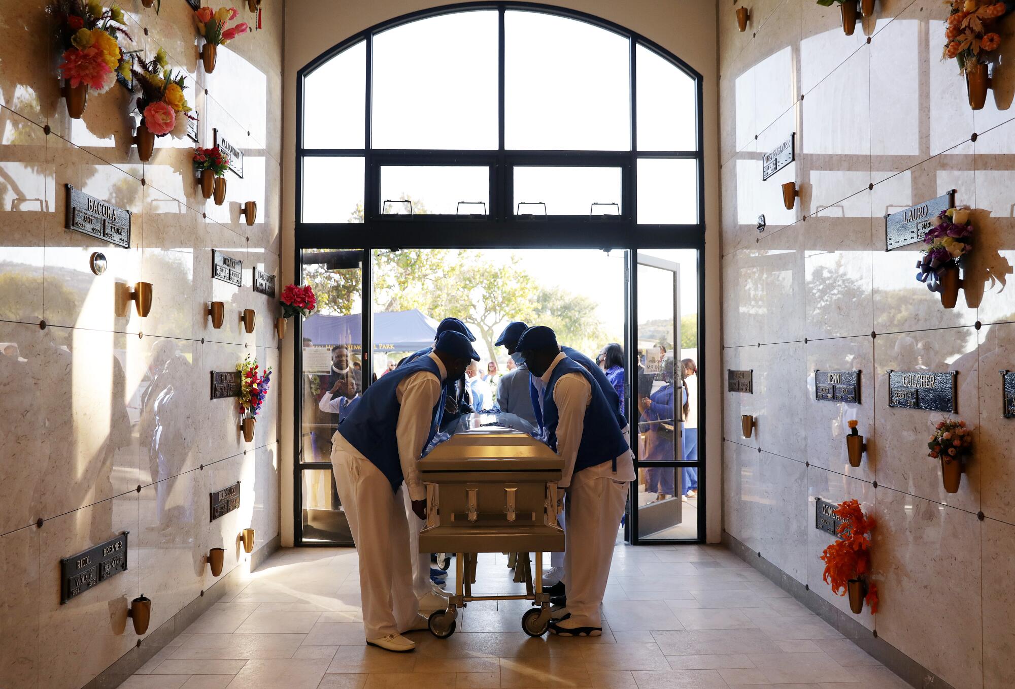 Pallbearers carry casket in a masoleum