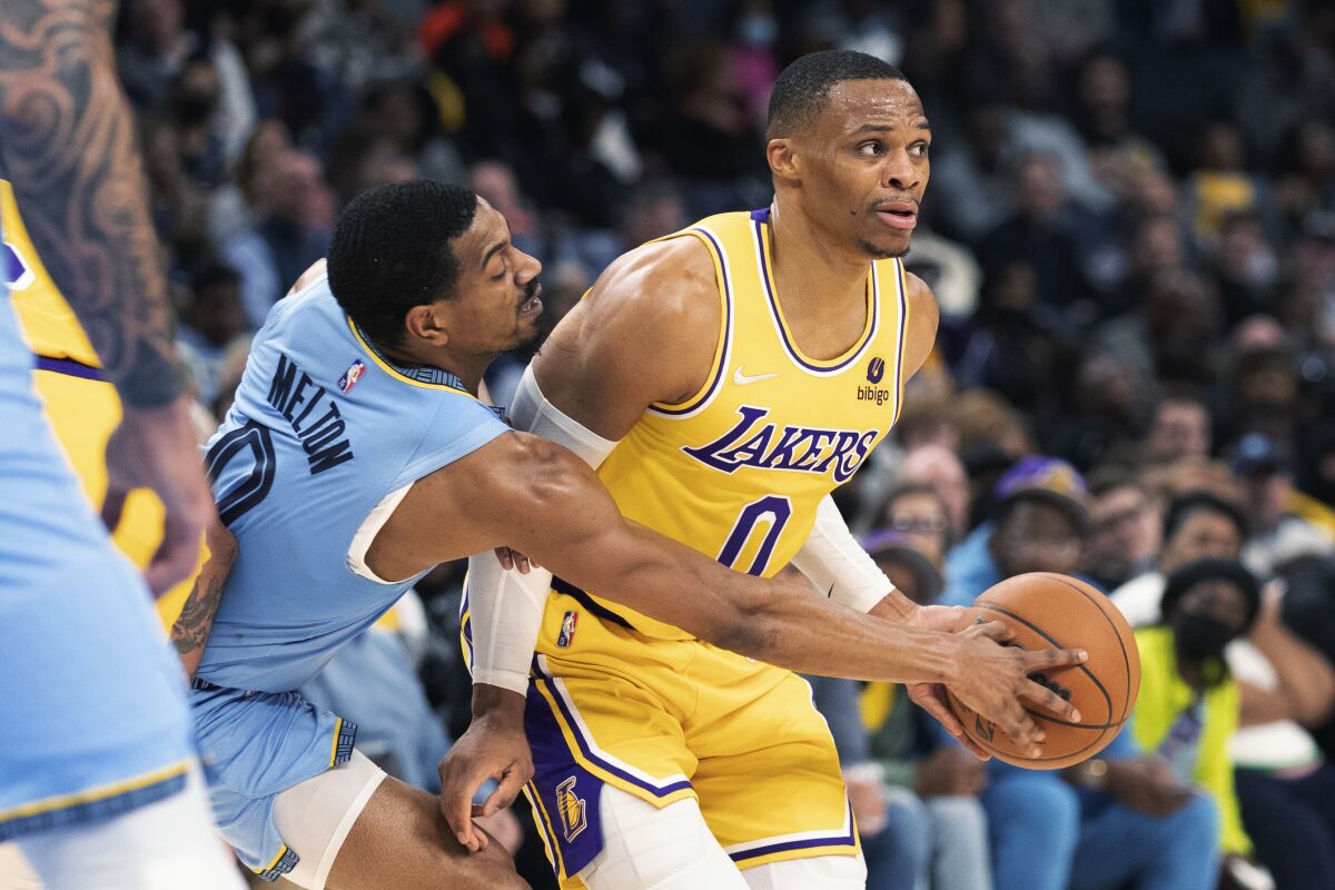 Grizzlies guard De'Anthony Melton attempts to knock the basketball away from Lakers guard Russell Westbrook.