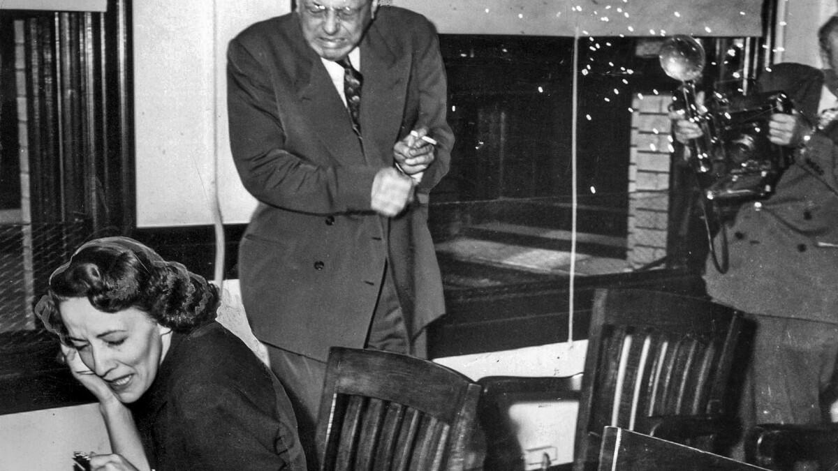 Doris Mae Normandine and attorney Werner O. Graf cringe as a Los Angeles Examiner photographer’s flashbulb explodes.