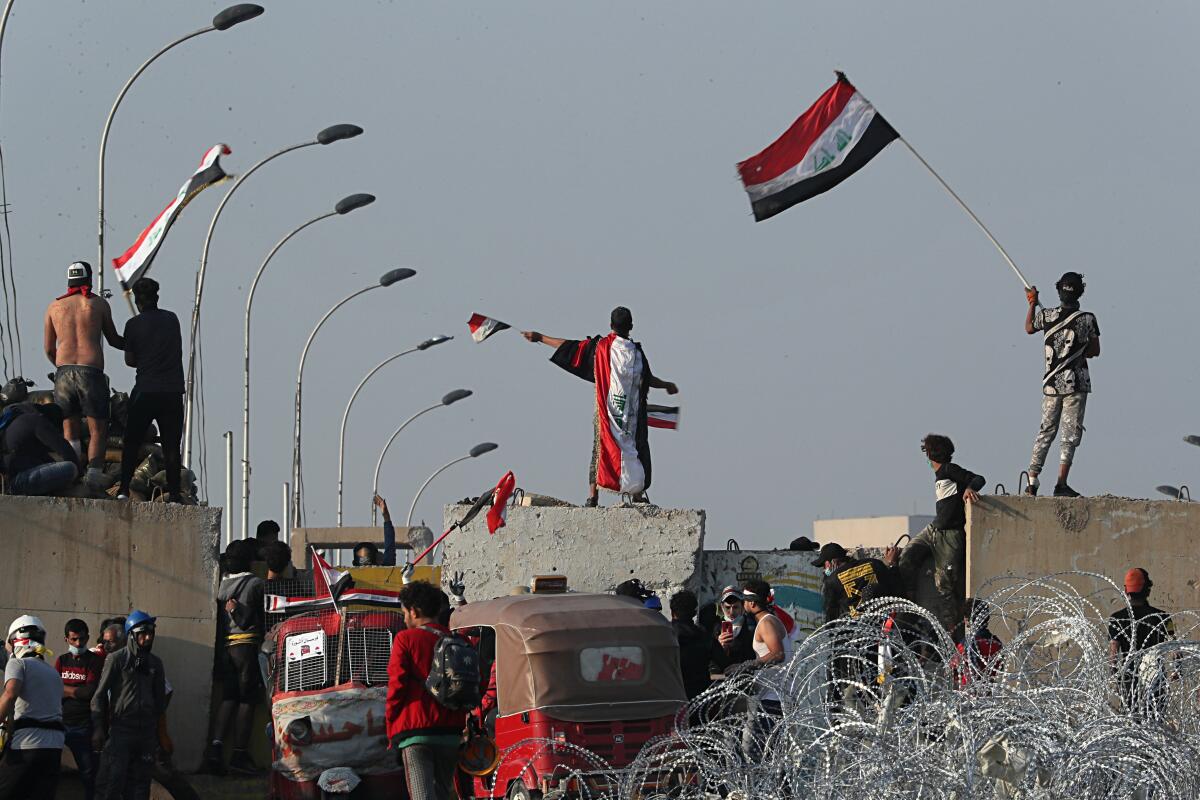 Iraqi anti-government protesters climb on walls and barriers set by security forces Oct. 31 near Baghdad's Green Zone.