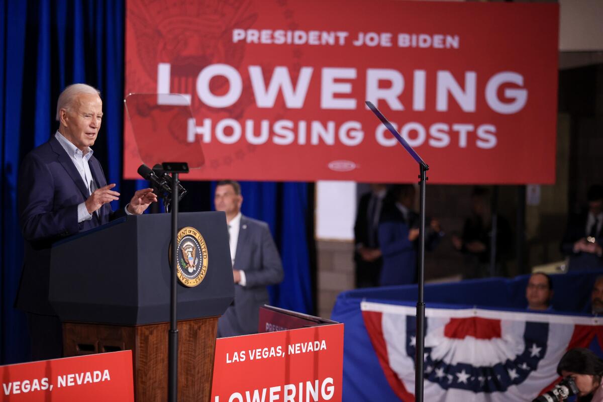 President Biden speaks in front of a banner reading "Lowering housing costs."