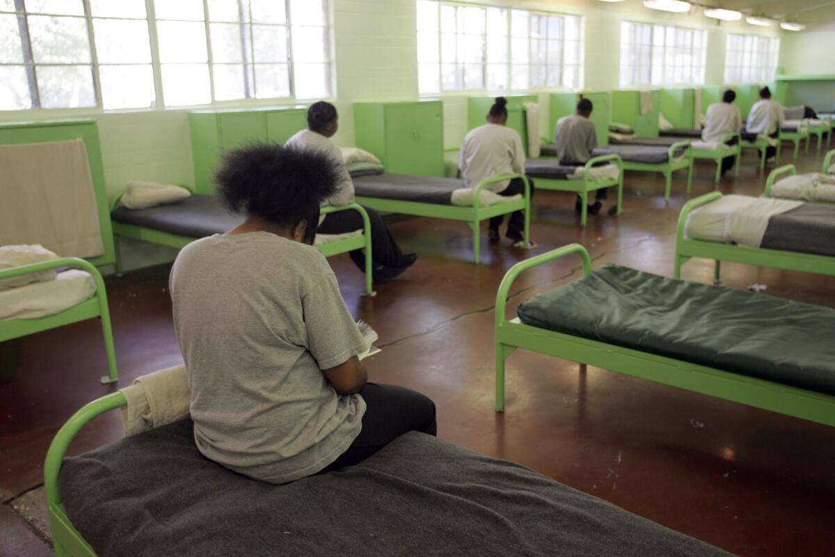 Girls at Camp Scott, a juvenile camp in Santa Clarita, sit quietly on their beds during a lunch break.