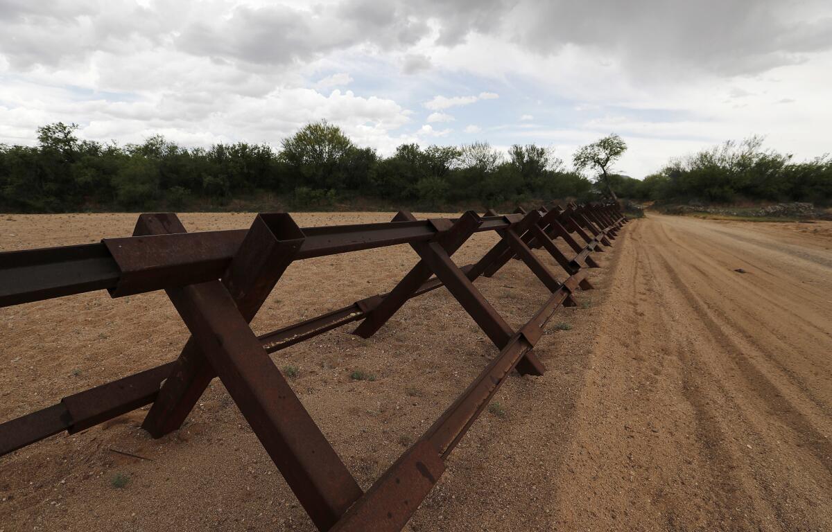 A vehicle barrier cuts across a dry wash along the U.S.-Mexico border in the Tohono O'odham Nation in Arizona. (Luis Sinco / Los Angeles Times)
