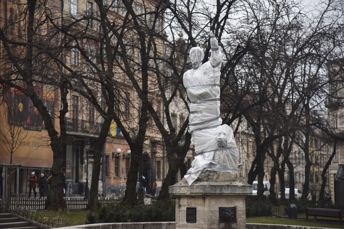 A sculpture in a town square is wrapped in plastic and duct tape. 