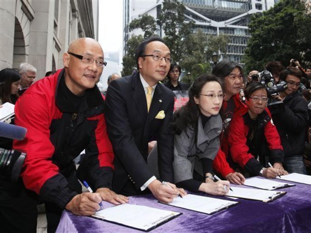 Five Hong Kong legislators, from left, Albert Chan, Alan Leong, Tanya Chan, Leung Kwok-hung and Wong Yuk-man sign the resignation letter outside the Legislative Council in Hong Kong Tuesday, Jan. 26, 2010. The five legislators have resigned to pressure China for democracy in this semiautonomous former British colony. The lawmakers from the League of Social Democrats and Civic Party signed and held up their resignation letters for photographers Tuesday, then handed them to the secretary of Hong Kong's Legislative Council. (AP Photo/Kin Cheung)
