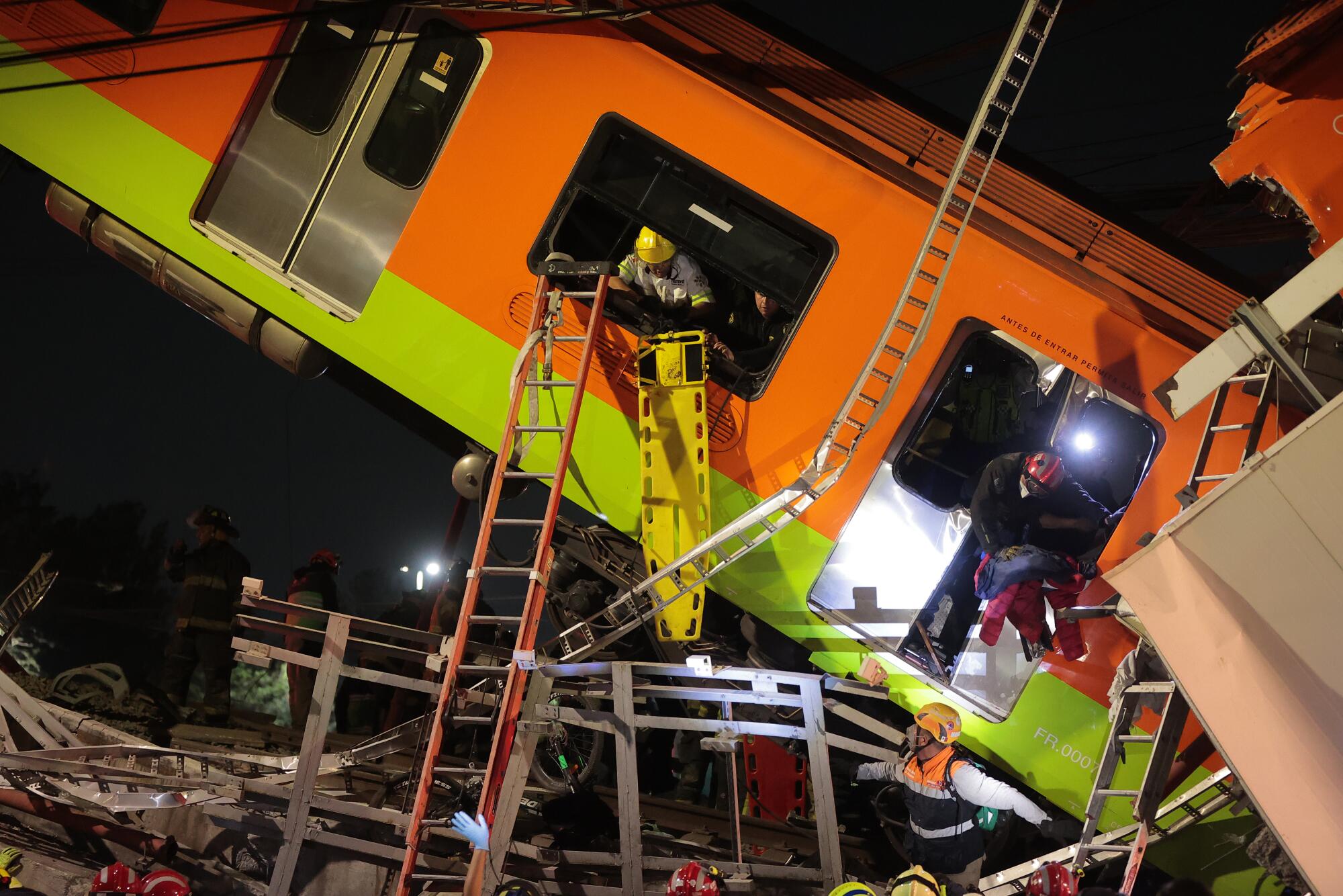 Emergency personnel search for accident survivors in a tilted subway car at night.