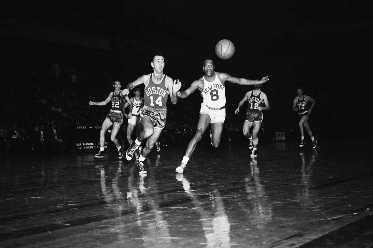 FILE - In this Nov. 12, 1955, file photo, New York's Nat “Sweetwater” Clifton (8) and Boston's Bob Cousy (14) race for a loose ball in an opening period of a basketball game at Madison Square Garden, in New York. Following chase, background, are Boston's Ed Macauley (22) and Togo Palazzi (12), and New York's Gene Shue. (AP Photo/File)