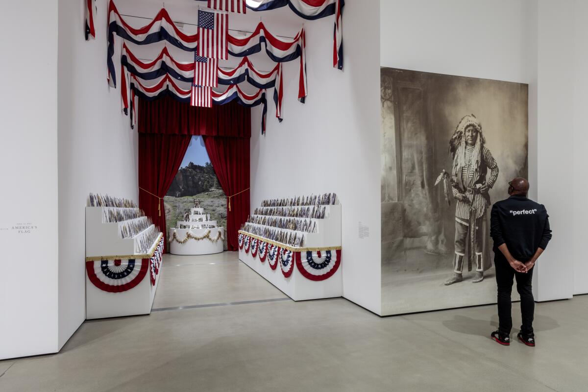 An installation of American flags and bunting alongside a portrait of a Native American