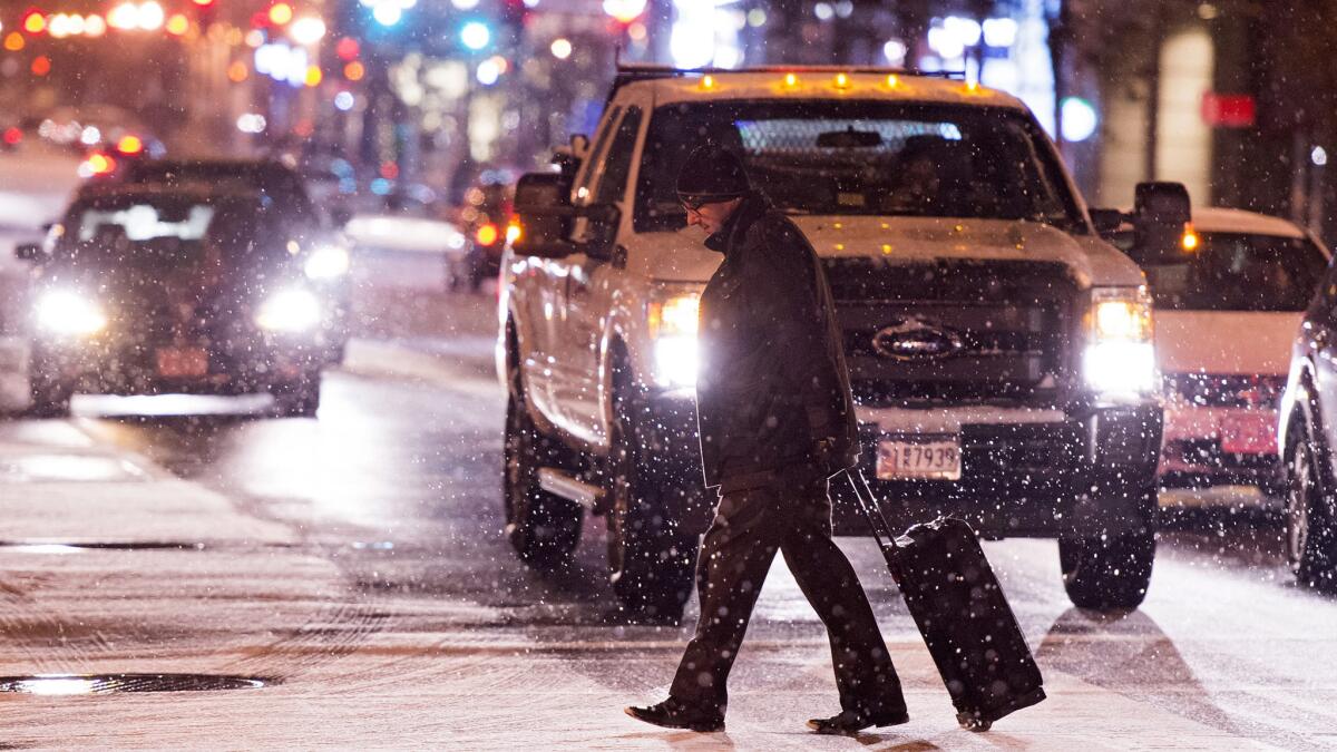 A pedestrian walks across a snow-covered street in downtown Washington on Thursday.