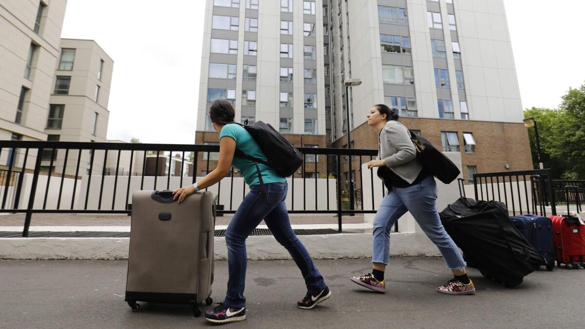 People with suitcases leave Taplow Tower residential block on the Chalcots Estate in north London on June 24, 2017, as residents evacuate because of fire safety concerns.