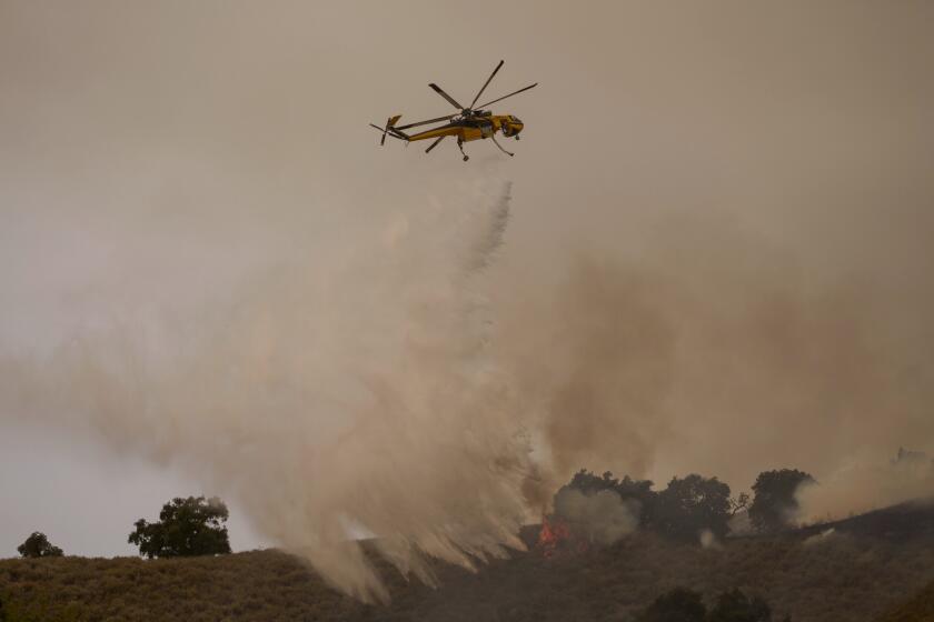 A helicopter drops water on flames from the advancing Lake Fire in Los Olivos, Calif., Saturday, July 6, 2024. (AP Photo/Eric Thayer)