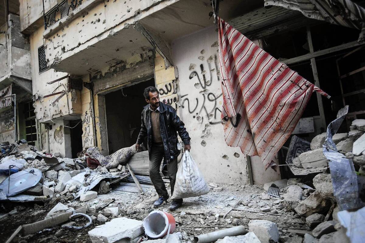 A man gathers belongings from his home in Aleppo, damaged by fighting between Syrian rebels and government forces.