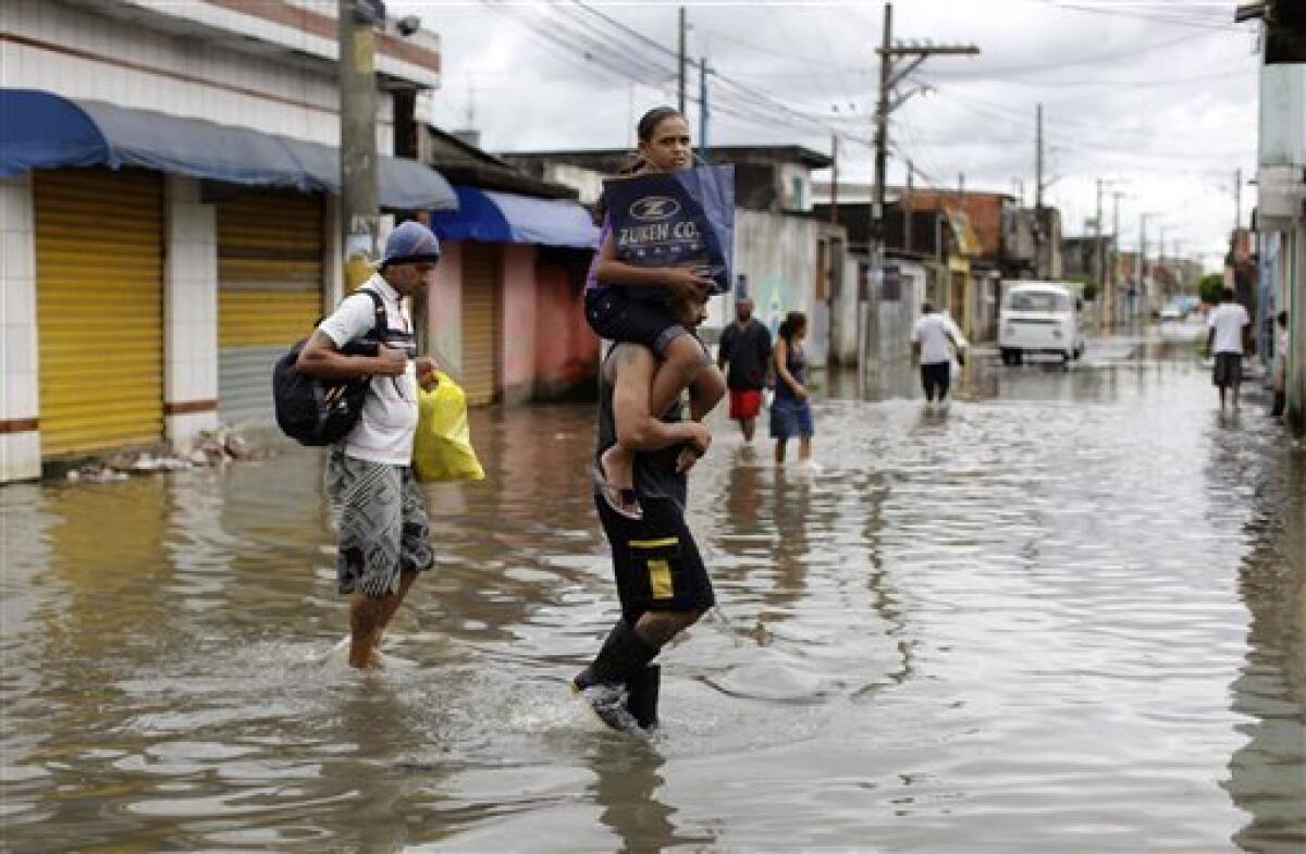 Residents, one carrying a girl on his shoulders, walk on a flooded street at Vila Itaim neighborhood in Sao Paulo, Brazil, Tuesday, Jan. 11, 2011. Brazilian authorities say heavy rains have triggered mudslides and floods in southeastern Brazil, killing at least 13 people. Sao Paulo state civil defense officials say 11 people died when their houses collapsed because of mudslides and two were killed in flash floods. (AP Photo/Nelson Antoine)