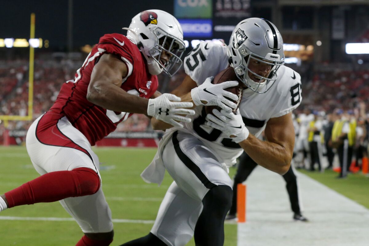 Oakland Raiders tight end Derek Carrier (85) scores a touchdown as Arizona Cardinals defensive back Rudy Ford defends during the first half on Thursday in Glendale, Ariz.