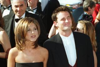 Jennifer Aniston and Matthew Perry stand together in formalwear and hold hands upon arrival at the 1995 Primetime Emmys