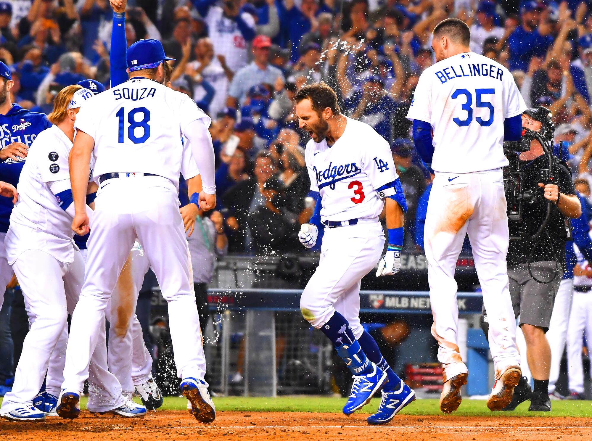 Chris Taylor celebrates with Steven Souza Jr., left, and Cody Bellinger among others while crossing home plate.