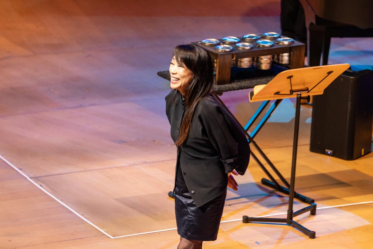 Unsuk Chin stands on the Disney Hall stage, her hands clasped behind her back.