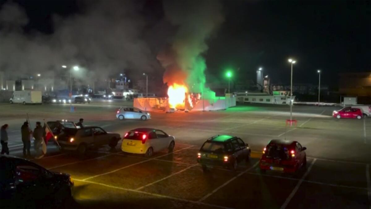 A structure is on fire at night in a lighted parking lot