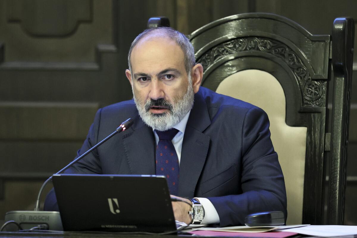 Armenian Prime Minister Nikol Pashinyan sits in an ornate chair in front of a laptop
